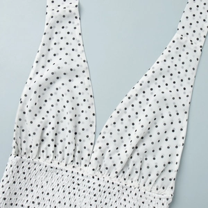Detail of the deep V-neckline and elastic smocked waist on a white polka dot dress