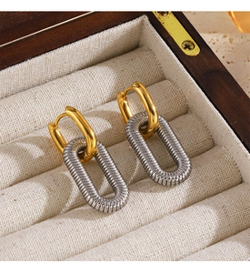 Detail of 18K gold hoop earrings with silver textured oval charms on linen cushion