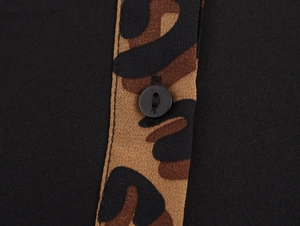 Detail aus schwarzem Strukturstoff mit Leopardenmuster-Borte und schwarzem Rundknopf