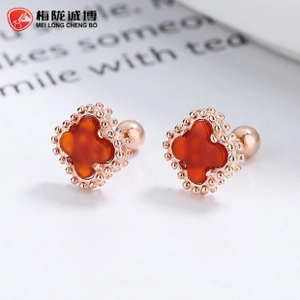Macro detail of rose gold clover stud earrings with red inlay and screw ball back