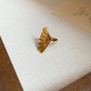 Artistic close-up of 18k gold plated stainless steel ginkgo leaf ring on fabric