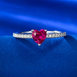 Macro shot of heart-shaped red gemstone ring with pavé stones on a blue velvet background
