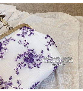 Detail of vintage evening bag with purple floral embroidery and gold clasp handle