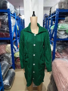 Detail of dark green cable knit cardigan with white buttons and textured knit pattern