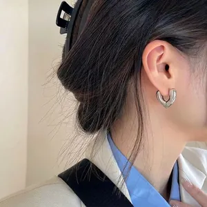 Minimalist silver heart-shaped hoop earring shown on a model with metallic finish
