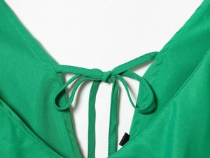 Detail of bright green V-neckline with delicate self-tie bow and woven fabric texture