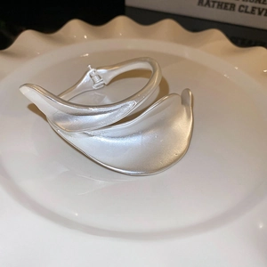 Detail of matte silver leaf design bangle on white decorative plate background