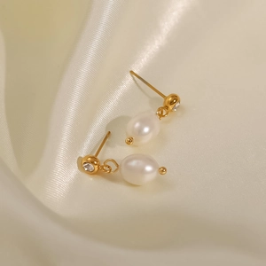 Vista macro de pendientes de perlas de agua dulce con cristal sobre seda elegante