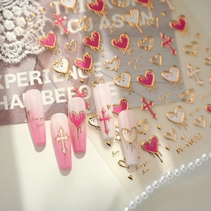 Pink gradient nail stickers with gold heart and cross designs on lace background