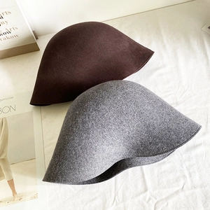 Détail de chapeaux cloches en laine bouclée marron et gris avec une texture chaude