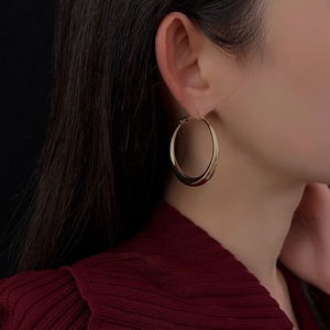 Close-up of elegant gold hoop earrings worn by a model on a soft dark background