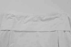 Détail d'une robe blanche montrant la large taille repliée et la texture du tissu lisse