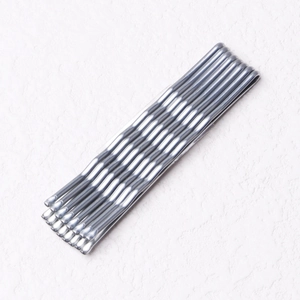 Detailed view of silver metallic bobby pins neatly arranged on a textured white surface