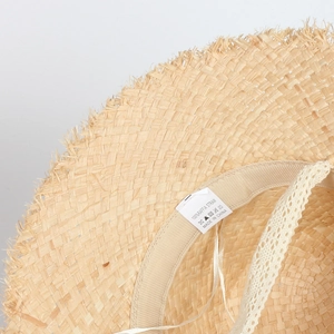 Detail of 100% raffia straw hat showing the inner label and fine weaving texture