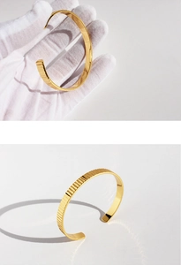 Dettaglio del bracciale rigido dorato a costine che mostra trama e flessibilità