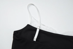 Détail d'un caraco noir avec bordure en dentelle blanche et bretelles réglables