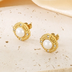 Detailed view of vintage gold stud earrings with a large center pearl and rhinestone halo