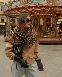Detail of beige tweed jacket with gold buttons and leopard print shawl in a city setting