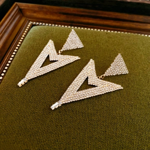 Detailed view of gold geometric triangle earrings encrusted with sparkling zircons