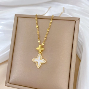 Close-up of gold titanium necklace with star clover pendant on champagne jewelry box
