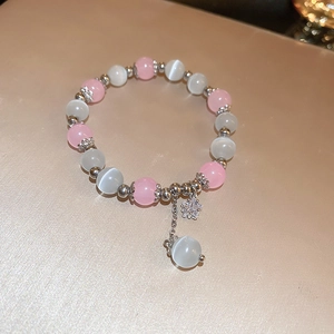 Detail of sweet beaded bracelet with pink cat eye stones and silver snowflake charm