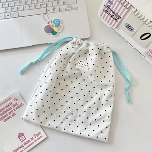 Macro detail of polka dot drawstring storage bag with soft blue cotton cords and woven label