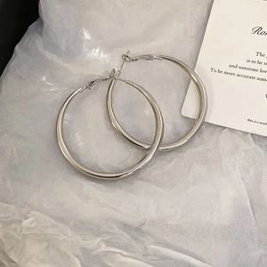 Close-up of minimalist silver circular hoop earrings on a decorative white paper backdrop