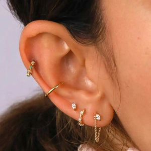 Close-up of gold S925 earrings featuring marquise zircon, tassel chain, and green gems