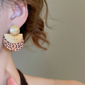 Gros plan sur des boucles d'oreilles léopard avec une texture en métal doré brossé