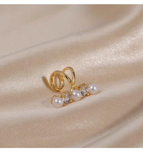 Detailed close-up of a gold ear cuff featuring alternating white pearls and zircon stones