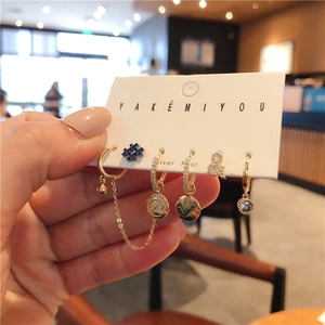 Close-up of a 6-piece gold earring set with zircon, symbols, and letters on a card