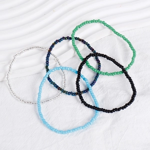 Close-up of colorful Bohemian seed bead bracelets stacked on a white textured background