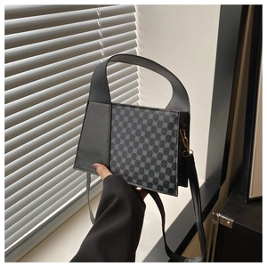 Détail d'un petit sac à main structuré avec motif monogramme et empiècements en cuir noir