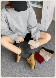 Close-up of knit crew socks in white, dark grey, and burgundy colors on a model