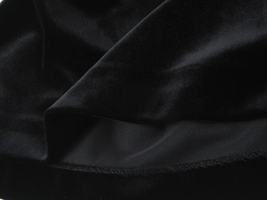Détail du tissu en velours noir montrant la couture exquise et la texture de l'ourlet