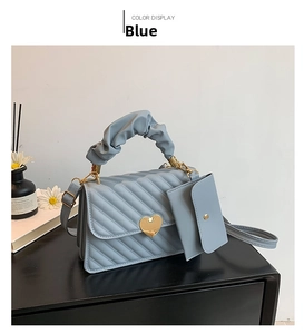 Detail of light blue quilted handbag set with gold heart clasp and cloud handle
