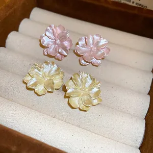 Elegant camellia flower stud earrings in pink and yellow pearl finish on jewelry box