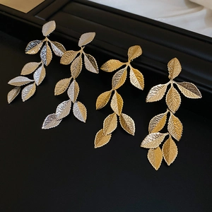 Detailed view of silver and gold leaf tassel earrings with textured metallic finish