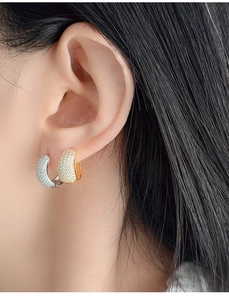 Detailed close-up of gold and silver S925 earrings with sparkling micro-pave zirconia