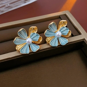 Detailed macro view of vintage light blue flower earrings with pearls and gold petals