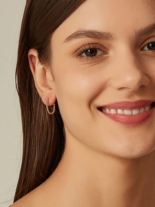 Detail of minimalist 14K gold-plated beaded hoop earrings worn by a smiling model