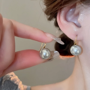 Close-up of elegant 18K gold pearl earrings worn by a model in a lifestyle setting