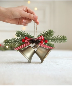 Weihnachtsdekoration mit goldenen Glocken, Tannenzweigen und Beeren in der Hand gehalten