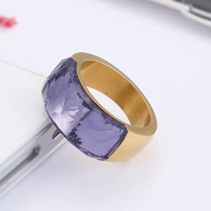 Macro shot of wide gold ring featuring a large faceted purple gemstone and smooth metal bezel
