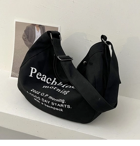Détail du sac fourre-tout en toile noire avec texte blanc et boucle argentée réglable
