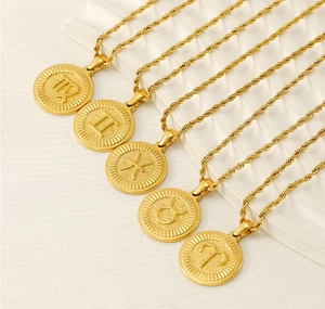 Detailed close-up of 18K gold zodiac pendants with embossed signs and twisted chains