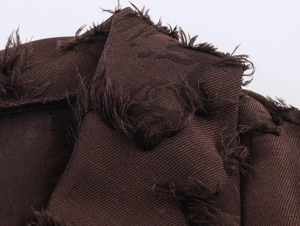 Makroaufnahme von dunkelbraunem Jacquard-Stoff mit Fransen-Textur für langes Winterkleid