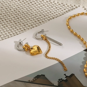 Detailed view of asymmetric gold heart studs and long tassel earrings with bead necklace