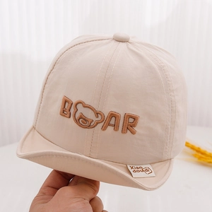 Close-up of beige baby baseball cap with bear embroidery and xiao doudi label detail