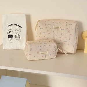 Detailed view of quilted makeup bags with cute bear and bow patterns on white shelves